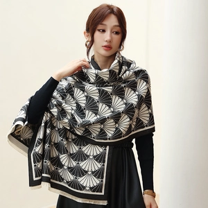 Detail of knit shawl scarf featuring black and white fan patterns and fringed edges