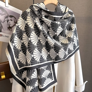 Detail of black and white fan pattern cashmere-like scarf with fringe on a wooden hanger