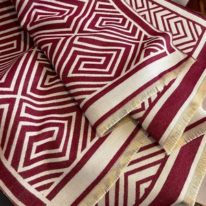 Nahaufnahme des geometrischen Labyrinth-Musters auf dem burgunderroten Schal
