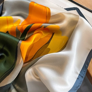 Eleganter Seidenschal mit gelben Tulpenmustern und edlem Glanz auf weichem grauem Grund