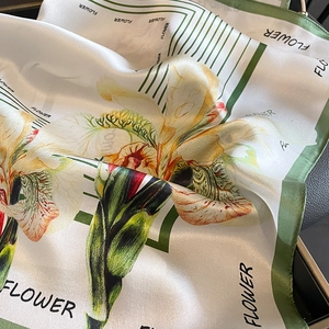 Floral print silk square scarf with green border and flower text in a soft drape
