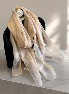 Detail of silk-like champagne scarf featuring golden butterfly embroidery and pearl beads
