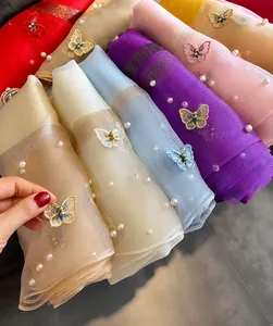 Detail of silk scarves with butterfly embroidery and pearls in various colors