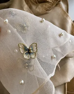 Close-up of champagne silk scarf with butterfly embroidery and delicate pearls