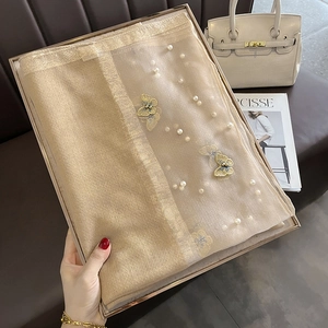 Détail d'une écharpe en soie dorée champagne avec perles blanches et broderie papillon