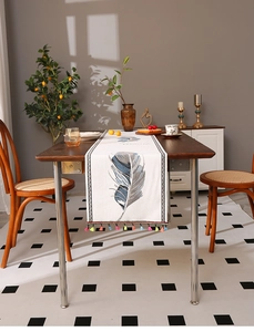 Primer plano del camino de mesa beige con plumas azules y bordes de borlas de colores