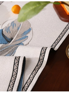 Primer plano de camino de mesa de lino con hojas azules y textura tejida sobre madera