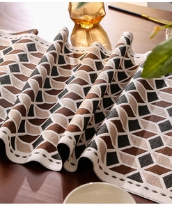 Detalle de camino de mesa jacquard con patrón geométrico sobre mesa de madera