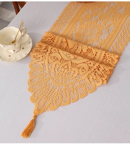 Macro detail of vintage orange lace table runner with intricate floral crochet and tassels