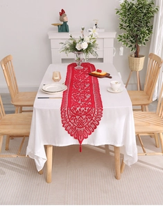 Close-up of red lace table runner featuring hollow-out patterns and handmade tassels