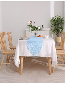Detail of light blue lace table runner with hollow floral patterns and elegant tassels