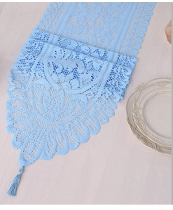 Detail of light blue lace table runner featuring floral crochet patterns and silk tassels