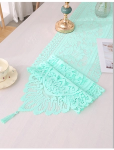 Detailed close-up of mint green lace table runner with floral patterns and tassels