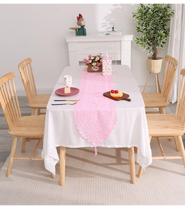 Close-up of pink lace table runner featuring hollow crochet patterns and fringe tassels