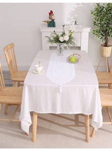 Macro detail of white hollow lace table runner with elegant fringe and tassel on wood table