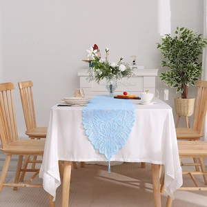 Light blue lace table runner with hollow design and fringe tassels on white cloth