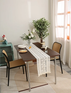 Detailed view of white hollow lace table runner with tassels on dark wooden table