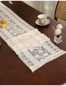 Detail of vintage hollow lace table runner with intricate floral patterns and tassels