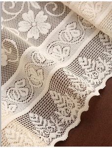 Close-up of beige vintage lace table runner featuring intricate floral jacquard patterns