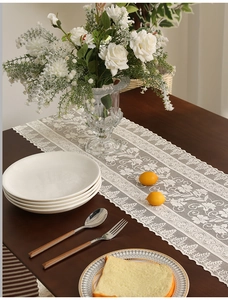 Close-up of intricate hollow lace table runner with floral patterns on dark wood