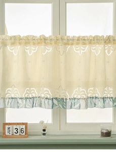 Detail of hollow floral lace cafe curtain with green botanical ruffled edge on a window
