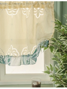 Detail of vintage beige lace curtain with floral patterns and green leaf ruffles