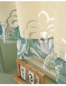 Detailed view of cream embroidered floral fabric with green leaf ruffle trim for cafe curtains