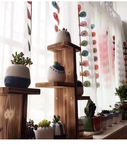 Detailed view of white sheer curtain with embroidered leaves behind wooden plant stand
