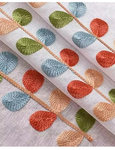 Dettaglio di ricamo a foglie colorate su tessuto di lino per tende da cucina