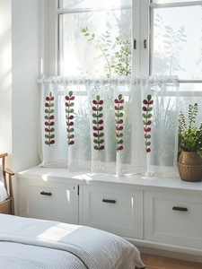 Detail of white semi-transparent cafe curtain with leaf embroidery and pom pom trim