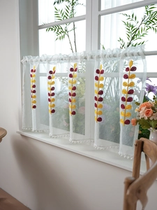 Detail of white semi-sheer coffee curtain featuring leaf embroidery and pom-pom trim edge