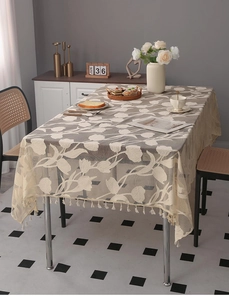 Detail of vintage beige lace tablecloth featuring floral patterns and fringe tassels