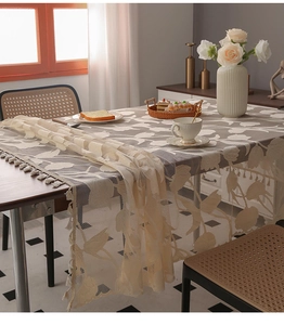 Detail of light beige lace tablecloth with leaf patterns and elegant tassel edges