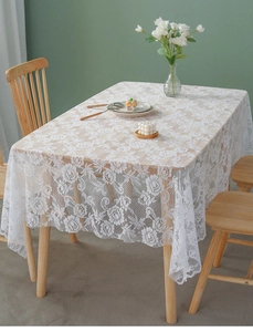 Close-up of white lace tablecloth featuring delicate floral embroidery and wavy edges