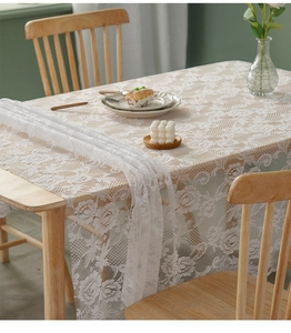 Close-up of white lace tablecloth featuring delicate rose floral patterns and wavy edges