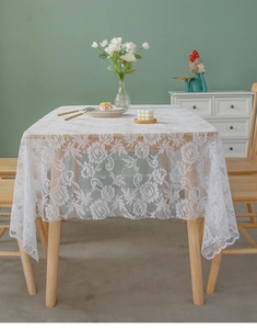 Detail of white lace tablecloth with vintage rose patterns and scalloped edges