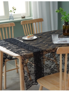 Close-up of elegant black lace tablecloth with rose floral hollow design and wavy edges