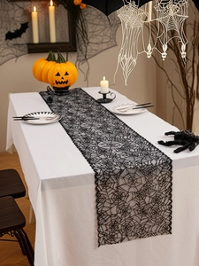 Detail van zwarte kanten tafelloper met spinnenwebmotief en geschulpte randen voor Halloween
