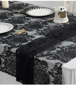 Detail of black lace Halloween tablecloth with skull and floral patterns on dining table