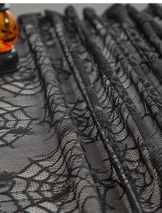 Detail of black spider web lace tablecloth with spooky Halloween pumpkin decoration