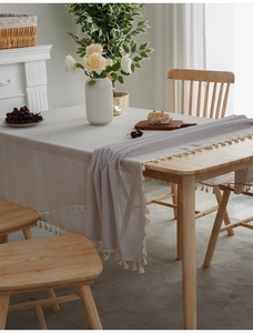 Detail of light gray linen tablecloth featuring elegant off-white tassel fringe edges