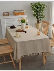 Detail of beige linen tablecloth with elegant fringe tassels in a cozy home setting