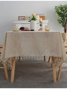 Close-up of linen tablecloth with decorative tassel edge and textured beige fabric
