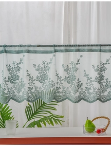 Detail of light green lace cafe curtain with crochet floral patterns and scalloped edges