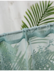 Close-up of mint green lace curtain detail with floral jacquard and rod pocket design