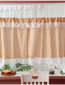 Detail of orange gingham cafe curtain with white ruffles in a cozy home setting