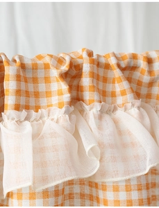 Detail of orange checkered lace curtain with white mesh trim and pleated edges