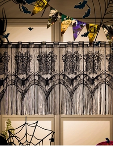 Detail of gothic black lace curtain featuring skull patterns and fringed tassels for Halloween