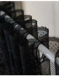 Detail of black mesh lace curtain with rod pocket design showing fine knit texture