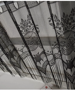 Close-up of black lace curtain featuring Halloween skull and bat patterns with fringe